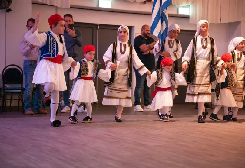 Kindergruppe in Tracht mit griechischer Fahne