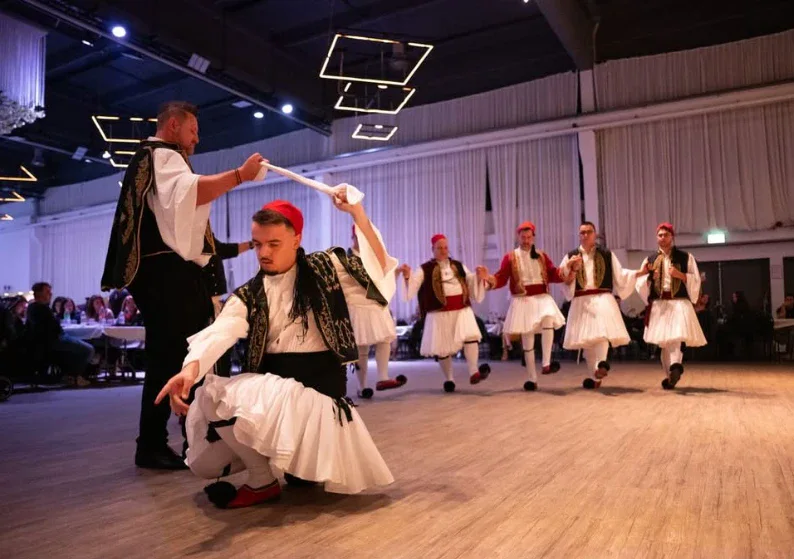 Tänzer in Fustanella tanzen den Tsamiko, der Vortänzer hält das Tuch